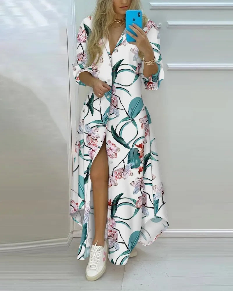 White ankle-length shirt dress with floral print, long sleeves, front buttons, and side slit paired with white sneakers.